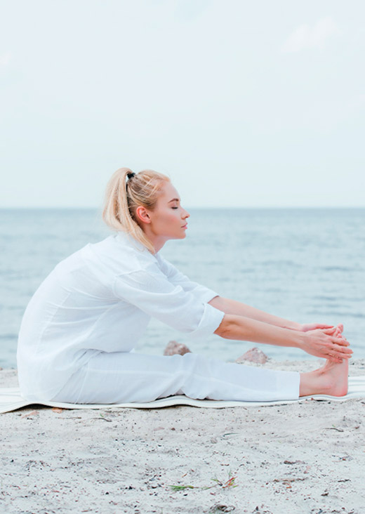 Mujer haciendo yoga frente al mar.